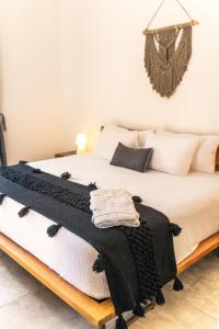 a bed with a black and white blanket on it at Panacea Condo Tulum in Tulum