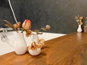 tre vasi bianchi con fiori su un tavolo di legno di L'Autre Rivière - Chambres d'hôtes a Ducey