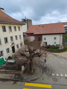 a building with a tree in the middle of a street at Studio Dante in Le Noirmont