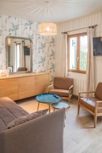 a living room with a couch and a mirror at Hôtel et Cottages Domaine Du Marquenterre in Saint-Quentin-en-Tourmont