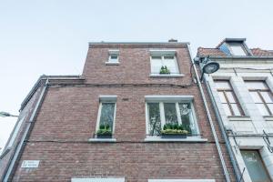 a brick building with two windows and potted plants at Les Potiers 1 - proche centre historique in Arras