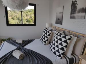 un lit avec des oreillers noirs et blancs et une fenêtre dans l'établissement Villa ARIA et MAQUIS, Villa 4 chambres- Piscine - Plage à pied - vue mer, à Pietrosella