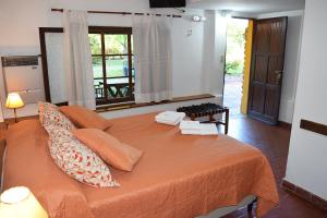 a bedroom with a bed with orange sheets and a window at Los Sauces Posada in Nono