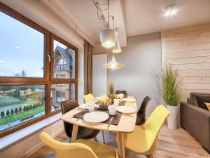 jadalnia ze stołem i żółtymi krzesłami w obiekcie VisitZakopane - Apres SKI Apartment w Zakopanem