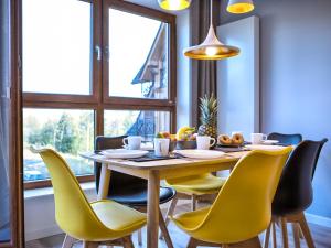 jadalnia ze stołem i żółtymi krzesłami w obiekcie VisitZakopane - Apres SKI Apartment w Zakopanem
