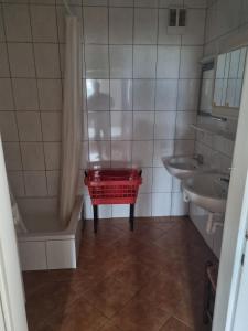 a bathroom with a tub and a sink and a red basket at Chalet Rosemarie in Bad Gastein