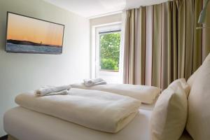 2 weiße Betten in einem Zimmer mit Fenster in der Unterkunft Insulaner Apartments in Helgoland