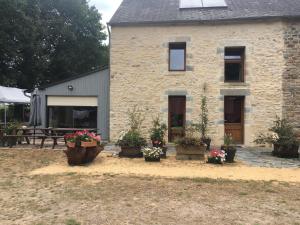 a stone house with potted plants in front of it at Le Clos Doré Parc in Bains-sur-Oust