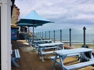 a row of picnic tables with an umbrella on the beach at The Two Lifeboats in Sheringham