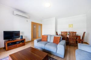 ein Wohnzimmer mit einem Sofa, einem TV und einem Tisch in der Unterkunft Apartment Baixa Marina in Olhão