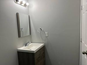 La salle de bains est pourvue d'un lavabo et d'un miroir. dans l'établissement Cozy Modern and Lavish 3 Bedroom Basement Suite, à Winnipeg