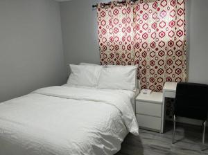a bedroom with a bed and a red and white curtain at Cozy Modern and Lavish 3 Bedroom Basement Suite in Winnipeg