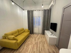 uma sala de estar com um sofá amarelo e uma televisão em Mojo-Jojo / a funky stay em Iaşi