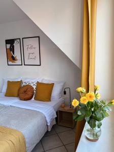 Old Town 2 Room Apartments في دوسلدورف: غرفة نوم بسريرين و مزهرية بها ورد اصفر