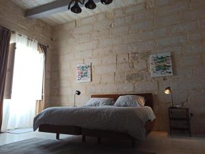 a bedroom with a brick wall with a large bed at Beautiful Studio apartment in Qormi Malta in Qormi