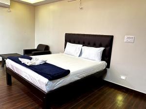 a bedroom with a bed with a black headboard and a chair at I Care With Greenery Comforts in Devanahalli-Bangalore