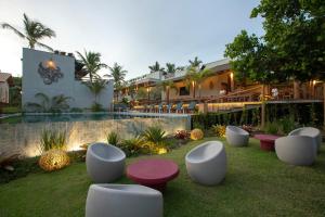 um resort com uma fila de cadeiras brancas e uma piscina em Santa Aldeia Hotel em Arraial d'Ajuda