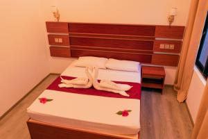 ein Schlafzimmer mit einem Bett mit zwei hölzernen Puppen darauf in der Unterkunft Feridhoo Inn in Feridhoo