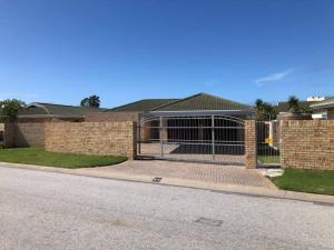 a fence in front of a brick house at Summerstrand holiday home in Summerstrand