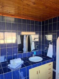 a blue tiled bathroom with a sink and a mirror at Summerstrand holiday home in Summerstrand