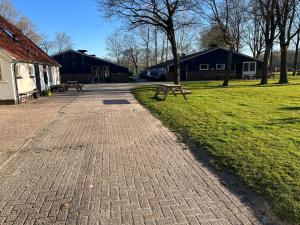 a brick walkway with benches in a park at Familiehuis voor 13 personen in Diever