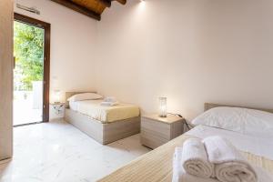 2 letti in una camera da letto con pareti bianche e finestra di Luxury Villa Ebe a Palermo