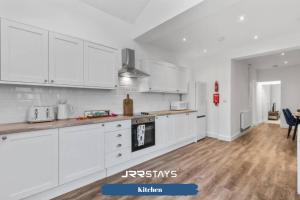 a kitchen with white cabinets and a wooden floor at Burton on Trent - 3 Bedroom, Sleep 6, Wi-Fi - JRR Stays in Burton upon Trent