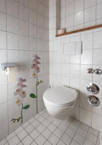 a bathroom with a toilet and flowers on the wall at Waldhauser Hof in Schönau am Königssee