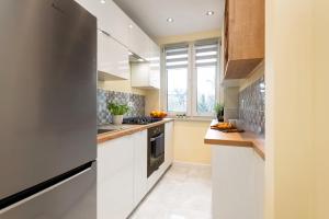 a kitchen with white cabinets and a large window at Apartament Chopin - ścisłe centrum - by Kairos Apartments in Gliwice