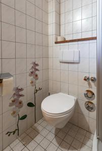 a bathroom with a toilet and flowers on the wall at Waldhauser Hof in Schönau am Königssee