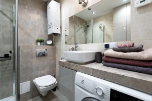 a bathroom with a sink and a toilet and a mirror at Apartament Chopin - ścisłe centrum - by Kairos Apartments in Gliwice