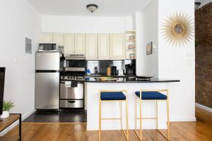 een keuken met witte kasten en een aanrecht met twee blauwe barkrukken bij 26-3B 1BR prime gramercy WD in unit Courtyard in New York