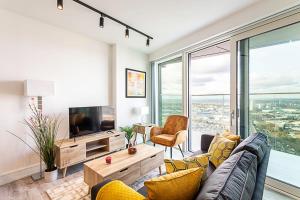 uma sala de estar com um sofá e uma televisão em Icon Tower Flat VI em Londres