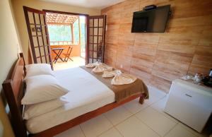 a bedroom with a bed with a tv on the wall at Suítes Sunset in Miguel Pereira