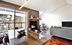 ein Wohnzimmer mit einem Esstisch und einem Kamin in der Unterkunft 569 chemin du Hibou in Stoneham
