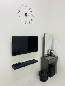 un reloj en la pared con una TV en la pared en I-STAY 01 JK Roomstay en Kampong Bemban