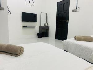 I-STAY 01 JK Roomstay في Kampong Bemban: غرفة بيضاء بسريرين وتلفزيون