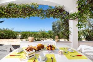 a table with food and a view of the ocean at Baia Degli Aranci Suite & Apartments in Vieste
