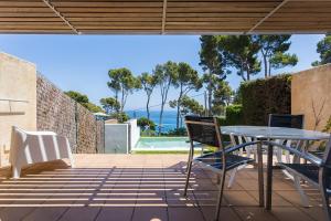 patio ze stołem i krzesłami oraz widokiem na ocean w obiekcie Luxury villa in front of the beach ONA w mieście Calella de Palafrugell