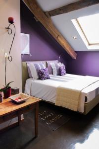 ein Schlafzimmer mit einem großen Bett mit lila Wänden in der Unterkunft O Sixième Sens in Williers