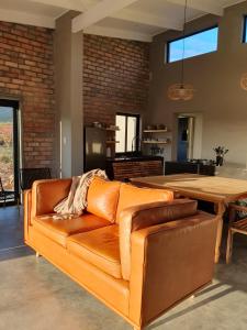 un canapé en cuir marron dans un salon avec une table en bois dans l'établissement Exhale Cottage, à Montagu