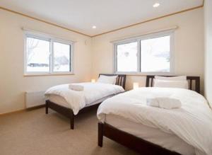 a bedroom with two beds and two windows at Ruby Chalet in Kutchan