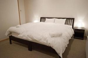 a bedroom with a large bed with white sheets and pillows at Ruby Chalet in Niseko