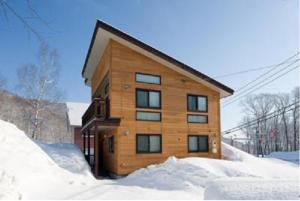 drewniany budynek w śniegu z śniegiem wokół niego w obiekcie Ruby Chalet w mieście Niseko