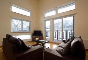 a living room with two couches and windows at Ruby Chalet in Niseko