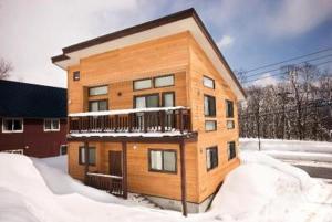 a building with a balcony in the snow at Ruby Chalet in Kutchan