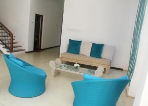 a living room with a couch and two blue chairs at Binnacle Negombo in Negombo