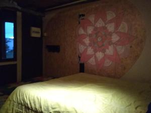 1 dormitorio con 1 cama con una flor en la pared en El Encuentro - Casa para 12 personas en Maldonado