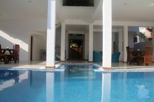 a swimming pool in a house with chairs and a table at Binnacle Negombo in Negombo