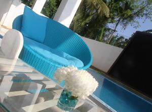 a glass table with a chair and a vase of flowers at Binnacle Negombo in Negombo
